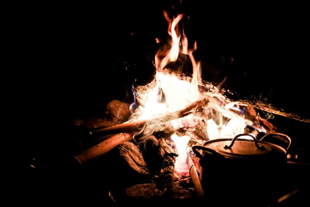 Delicious camp Dutch oven recipes cooking over a crackling campfire in a natural outdoor setting, highlighting the versatility of cast iron for gourmet camping food.