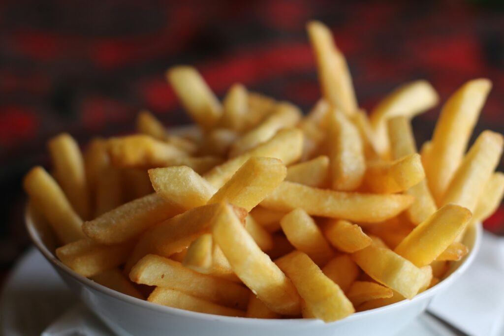 A batch of crispy, golden french fries being lifted from the basket of a Ninja Crisper, illustrating the healthy and delicious results from an air fryer.