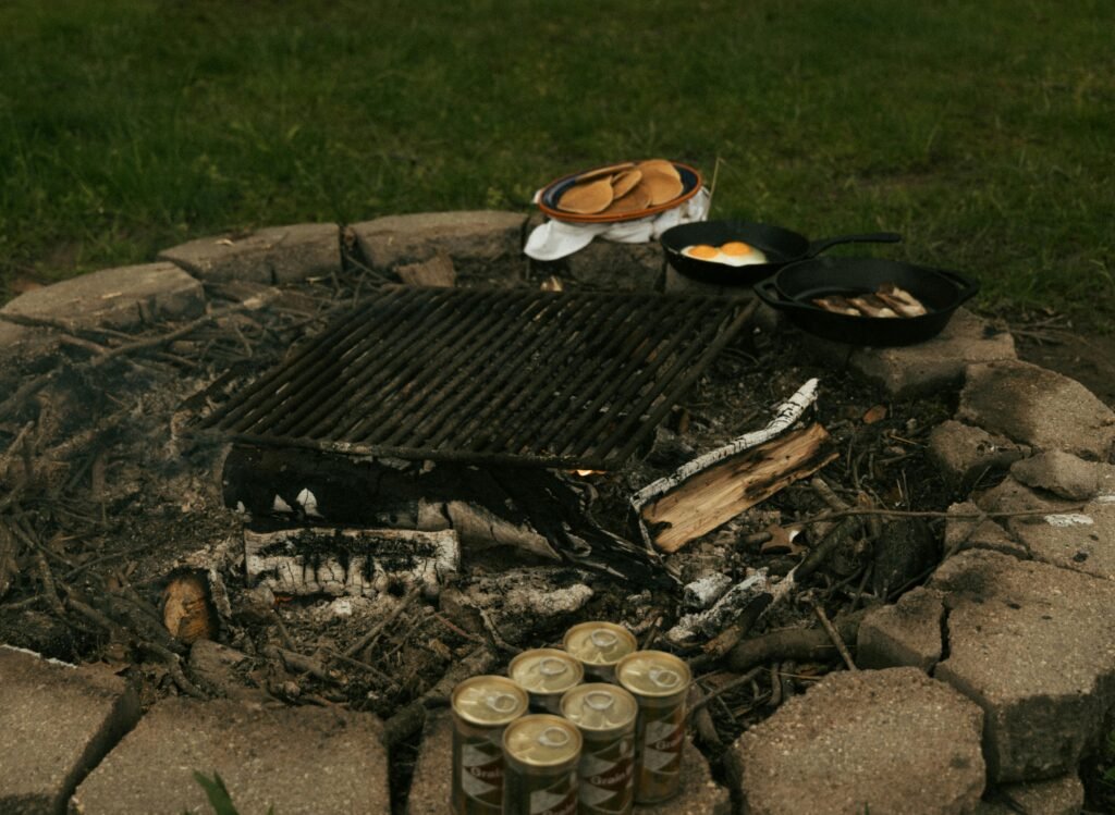 A hearty one-pan camping breakfast of eggs and hash cooking in a cast-iron skillet over a campfire, illustrating an easy meal idea for the outdoors.