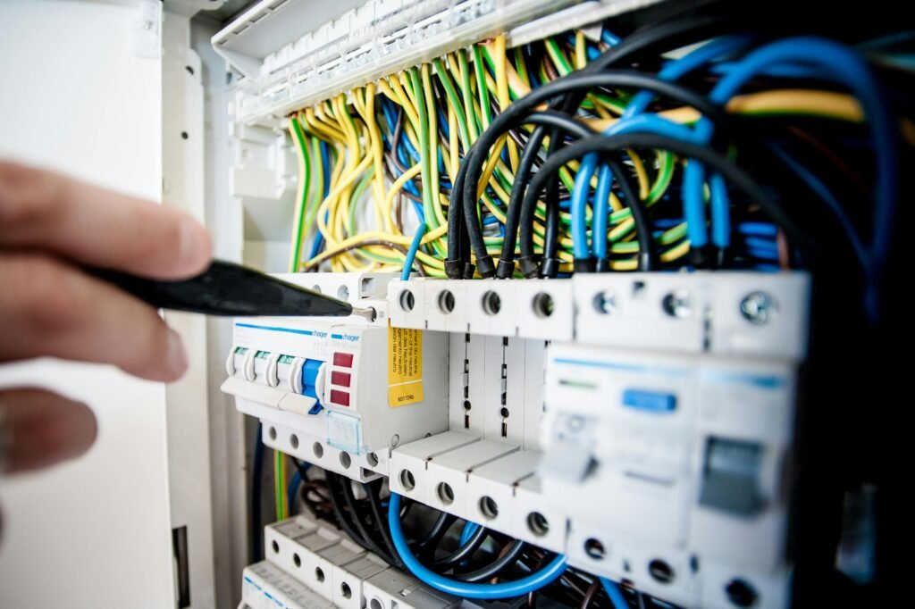 A person's hand installing a new coil burner electrical component into an electric stove cooktop to fix it.