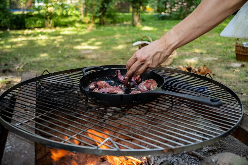 A hearty campfire meal sizzling in a cast-iron skillet over glowing embers, illustrating an essential and delicious part of the outdoor camping experience.