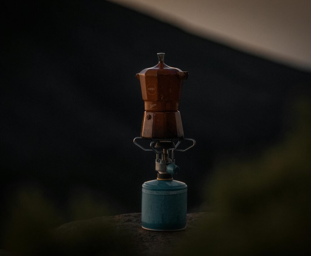 Portable gas burner outdoor cooking setup with a pot on the flame at a campsite, highlighting convenient and efficient outdoor meals.