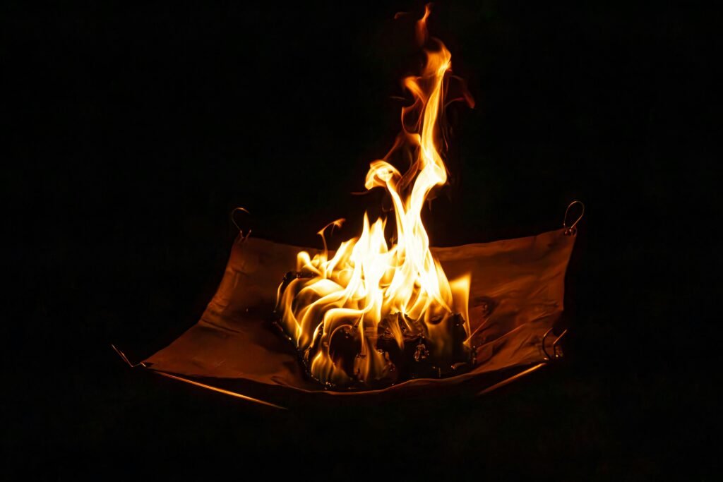 Portable wood burning stove in use at a campsite, with a kettle boiling and a warm glow, representing efficient outdoor cooking and cozy camping warmth.