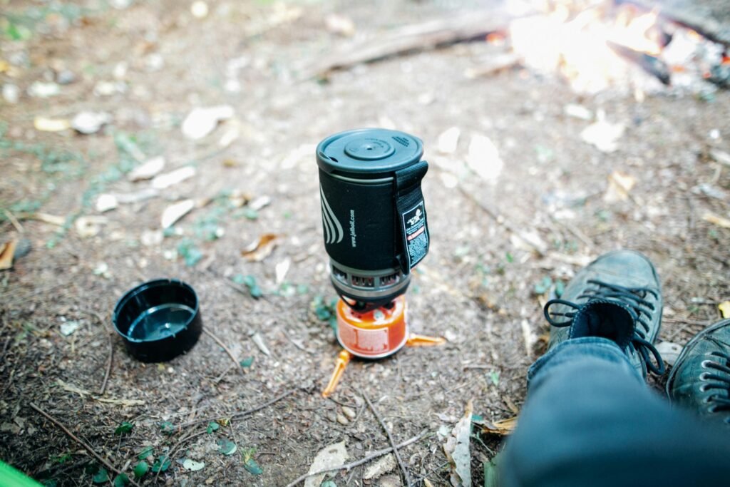 A person cooking a meal on a portable 2 burner stove at a beautiful campsite, showcasing the best gear for an outdoor adventure.