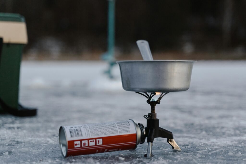 A person cooking a meal on a portable 2 burner propane stove at a scenic campsite.