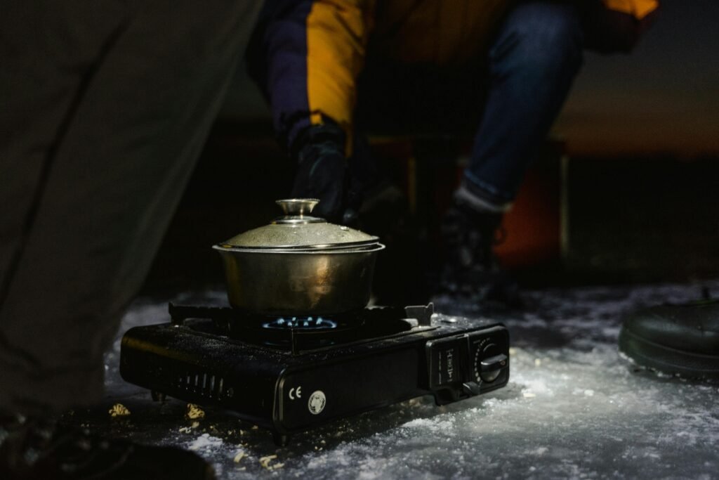 A powerful gasoline stove in action, boiling water for a backpacker during a winter camping adventure in a snowy mountain setting.