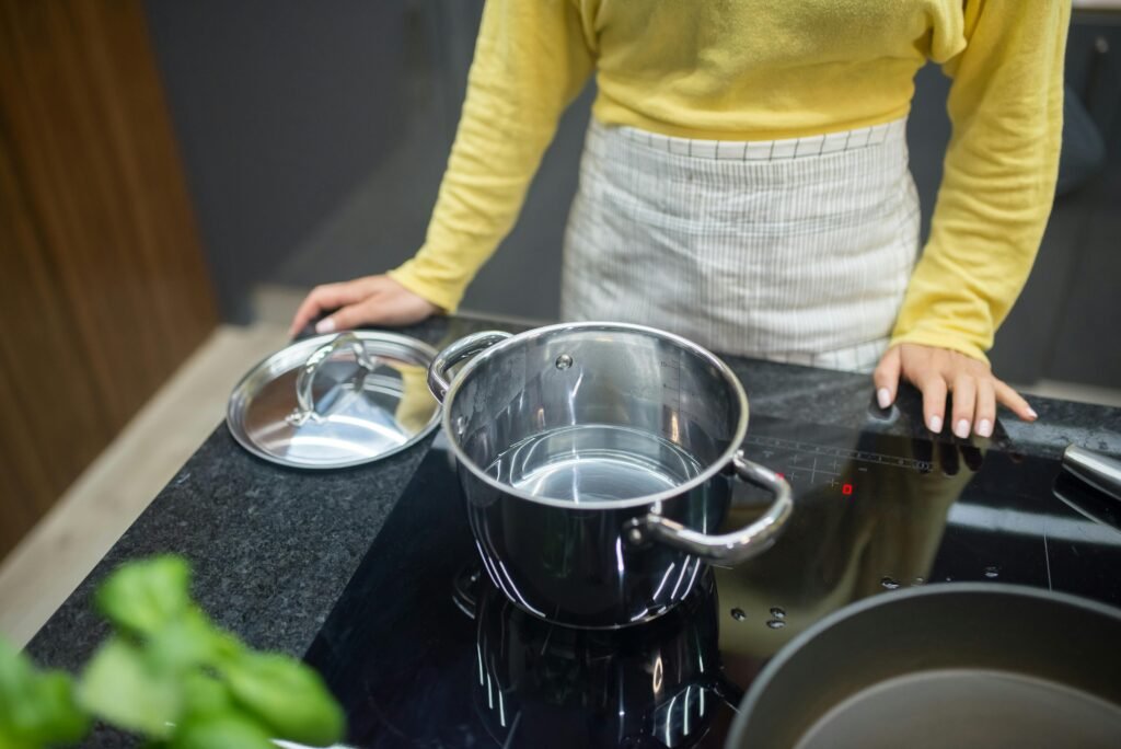 A pot simmers on a sleek, black portable electric stove, demonstrating a convenient cooking solution for small spaces.