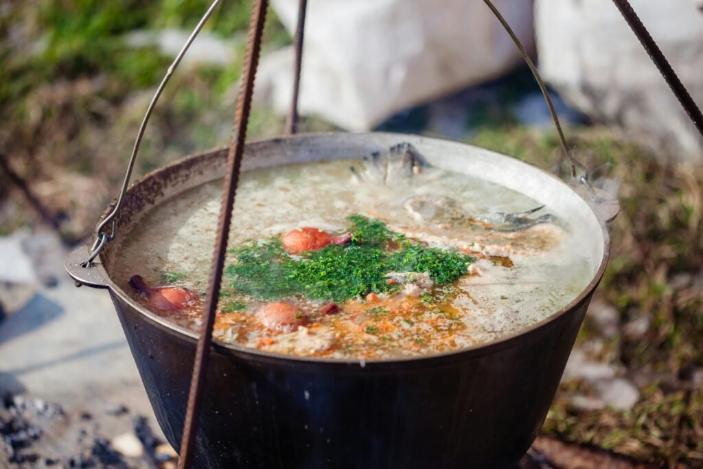 A delicious one-pot camp food meal simmering in a cast-iron Dutch oven over a crackling campfire, illustrating an easy and enjoyable outdoor cooking experience.